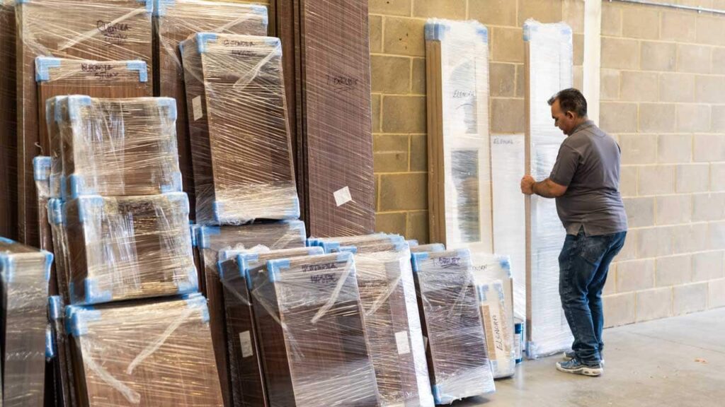 A person in a warehouse, arranging materials for crafting a wardrobe