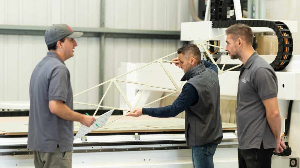 A team of craftsmen carefully measuring and assembling wardrobe components.