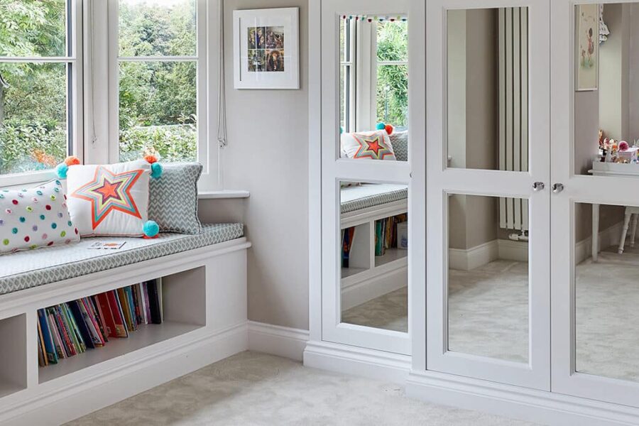 A luxurious fitted wardrobe complemented by a stylish window seat and shelves