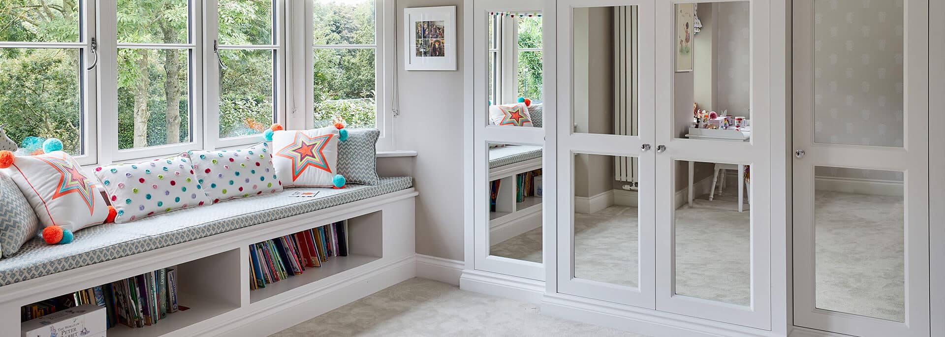 A luxurious fitted wardrobe complemented by a stylish window seat and shelves