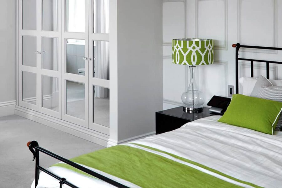 Green and white bedroom design with fitted wardrobes