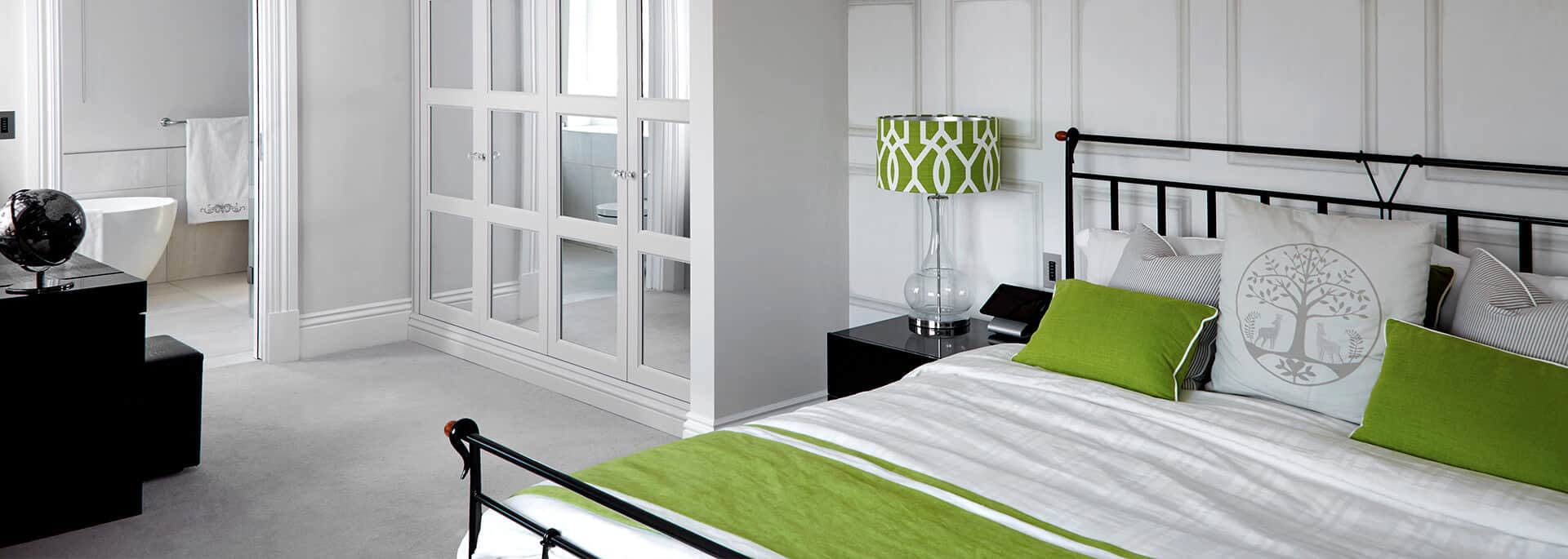 Green and white bedroom design with fitted wardrobes