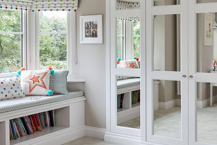 A luxurious fitted wardrobe complemented by a stylish window seat and shelves