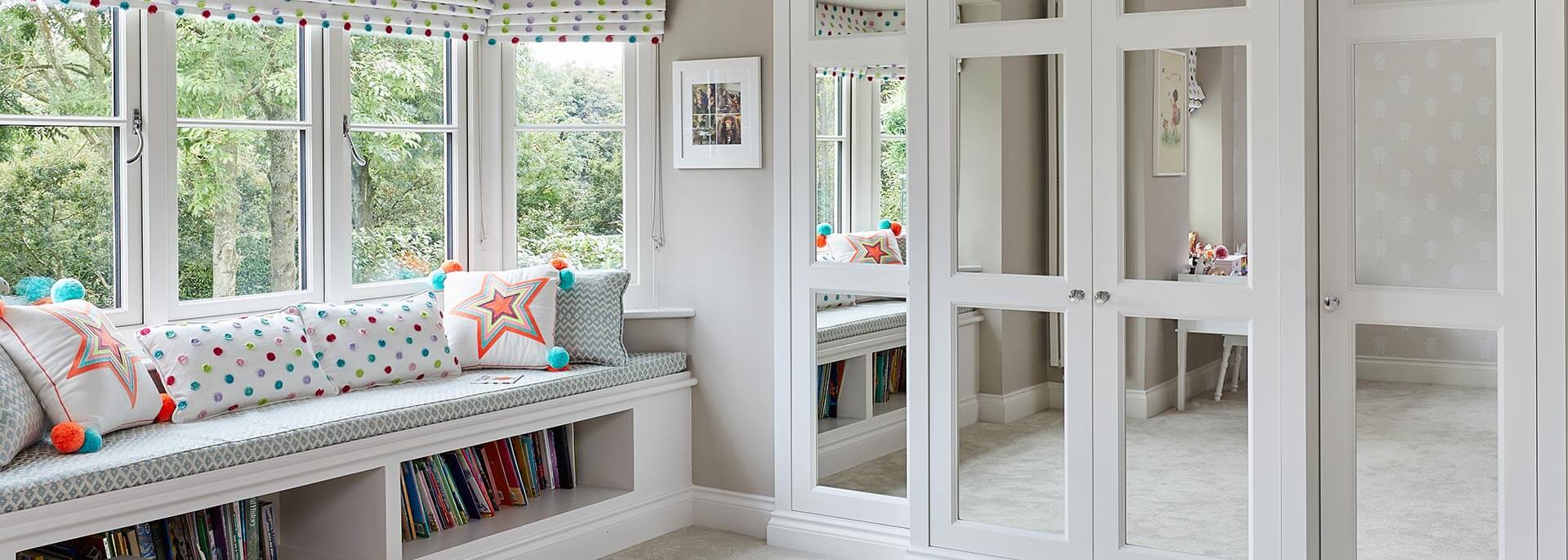 A luxurious fitted wardrobe complemented by a stylish window seat and shelves