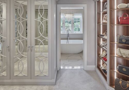 Bespoke fitted wardrobes and shelving with door leading into bathroom