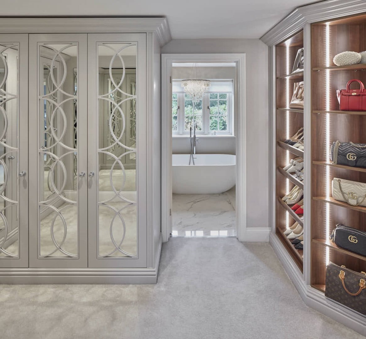 Bespoke fitted wardrobes and shelving with door leading into bathroom