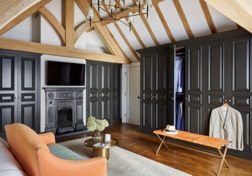 Monochromatic dressing room with lively accents: vibrant chair, couch, and decorative vase for added character