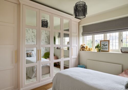 pink fitted wardrobes with panelled mirrored doors.