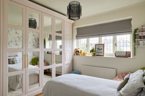 Pink fitted wardrobes with sectioned mirrored doors in a bedroom setting
