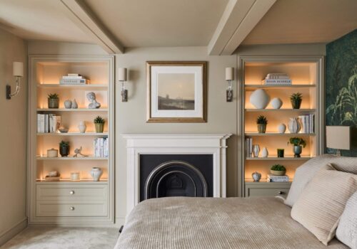 Matching Victorian style built-in shelving either side of fireplace in a bedroom - with light on
