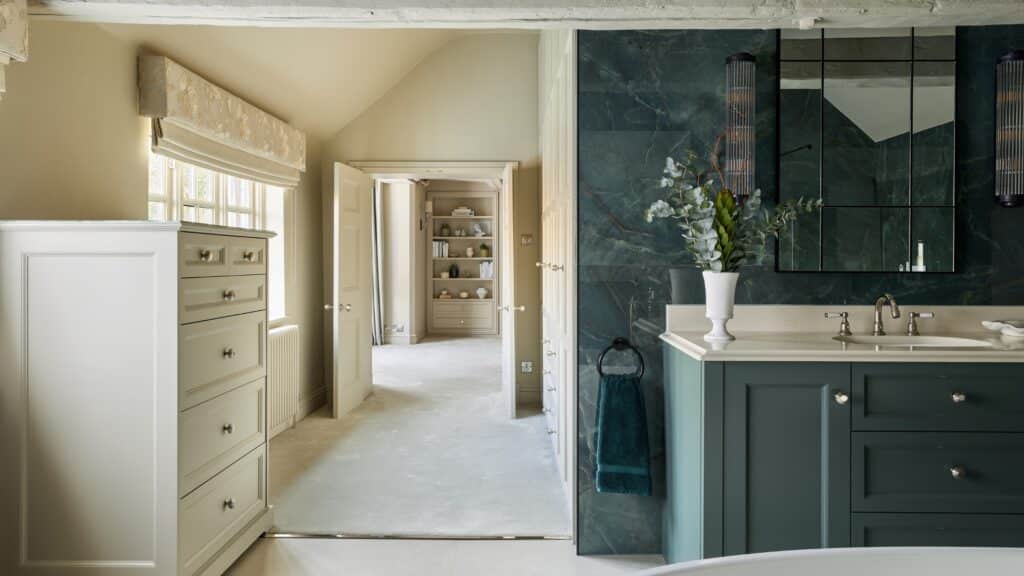 Heritage Wardrobes - Wall Hall4066-2560x1440 a tall boy in the hallway with a his and hers vanity unit in the bathroom looking through to a full custom built dressing room